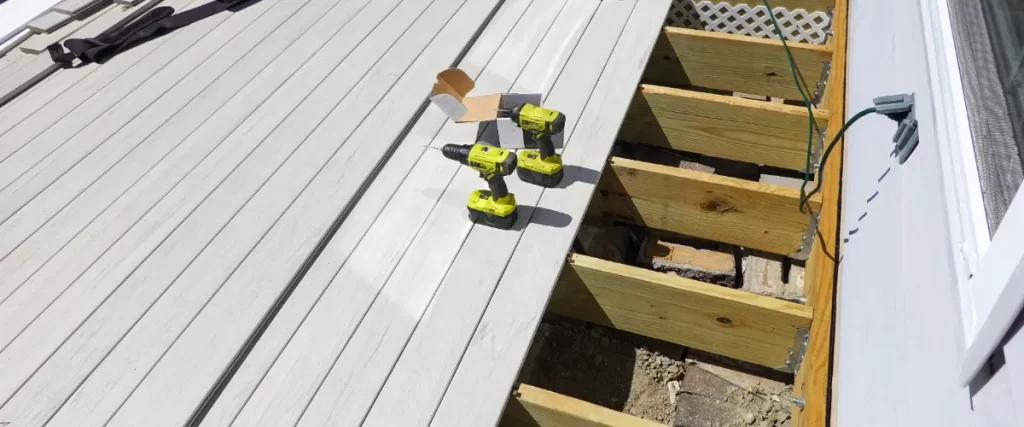 a composite deck installation in progress with grey boards and a drill