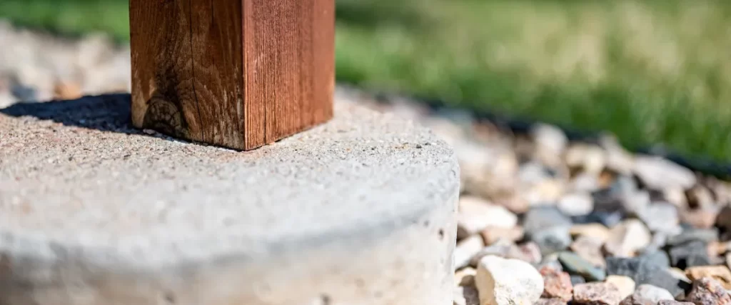 a wooden deck post supported by a concrete footing
