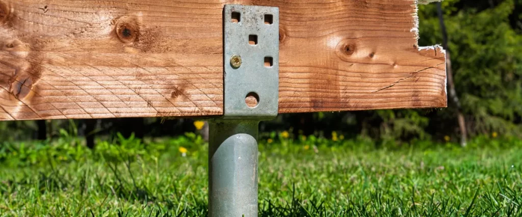 a wooden deck support post featuring a ground screw foundation