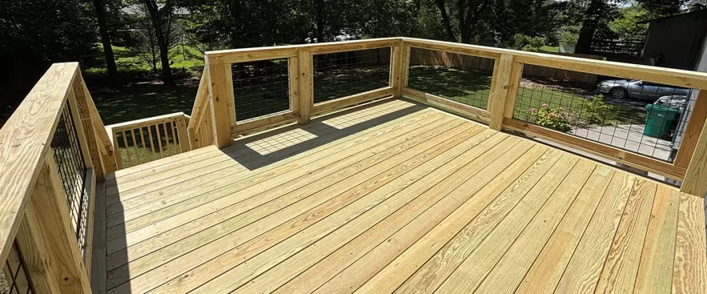Pressure-treated wood deck with wire railing and backyard stairs on elevated outdoor living space