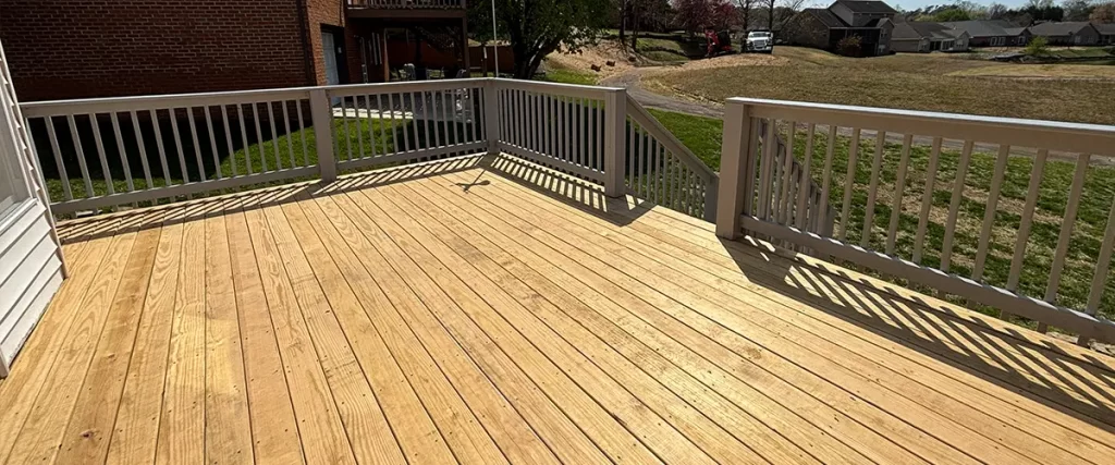 Pressure-treated wood deck with gray railing and backyard stairs on elevated outdoor living space